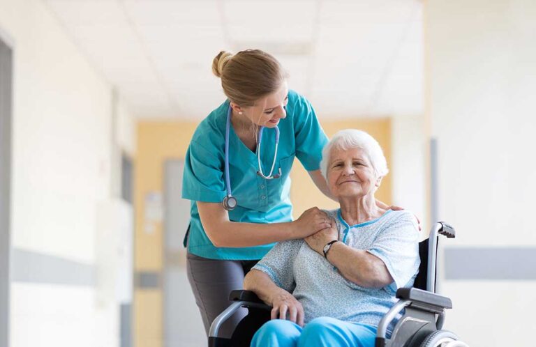 Senior residents speaking to a staff member at a table in a comfortable common room.